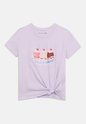 Μωβ παιδικό T-shirt με μπροστινή εικονογράφηση ενός επιδόρπιου banana split με τρεις μπάλες παγωτού και κερασάκια, με κόμπο μπροστά.