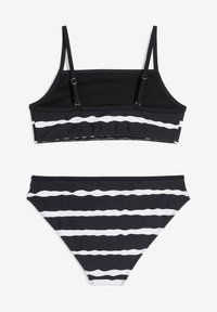 Completo bikini a righe bianche e nere con top corto dotato di spalline regolabili e slip a vita alta con un motivo ondulato.