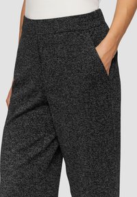 Pantalons gris texturés présentant un motif légèrement moucheté, une taille élastique et des poches latérales. Le matériau semble doux et confortable.