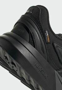 Čierna športová obuv s textúrovaným zvrškom vyrobeným z materiálu Cordura, pevnou gumovou podrážkou a značkou "Lightstrike" na medzipodrážke.