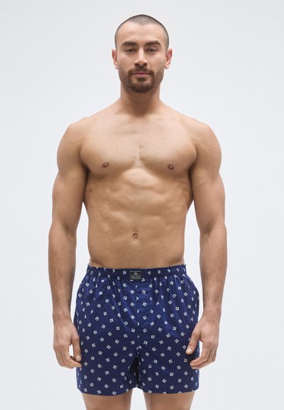 Námornícky modré boxerky z mäkkej látky, s opakujúcim sa bielym geometrickým vzorom a elastickým pásom s logom.