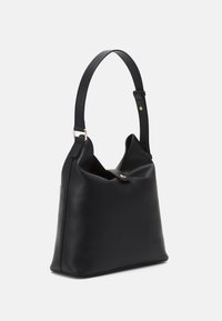 Svart läderhandväska med en slät textur, unik vikdesign, ett justerbart axelband och accentuerande detaljer i guldton.