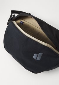 Black bag with a textured fabric exterior, featuring a zippered closure and a tan interior. A subtle logo is embossed on the side.