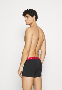 Boxers ajustados negros de Nike con una banda elástica roja que presenta el nombre y el logo de la marca. Tejido suave, ajuste ceñido y longitud hasta mitad del muslo.