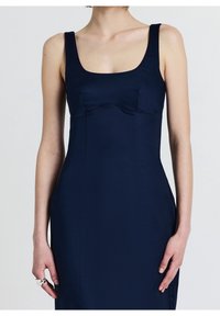 Robe ajustée bleu marine avec encolure carrée, larges bretelles et détails de coutures. Confectionnée dans un tissu lisse avec une silhouette structurée.