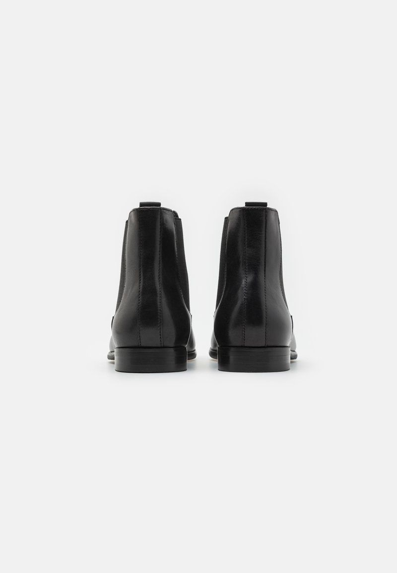 Czarne skórzane botki za kostkę z gładkim wykończeniem, elastycznymi bocznymi panelami i małą pętelką z tyłu. Płaskie gumowe podeszwy.