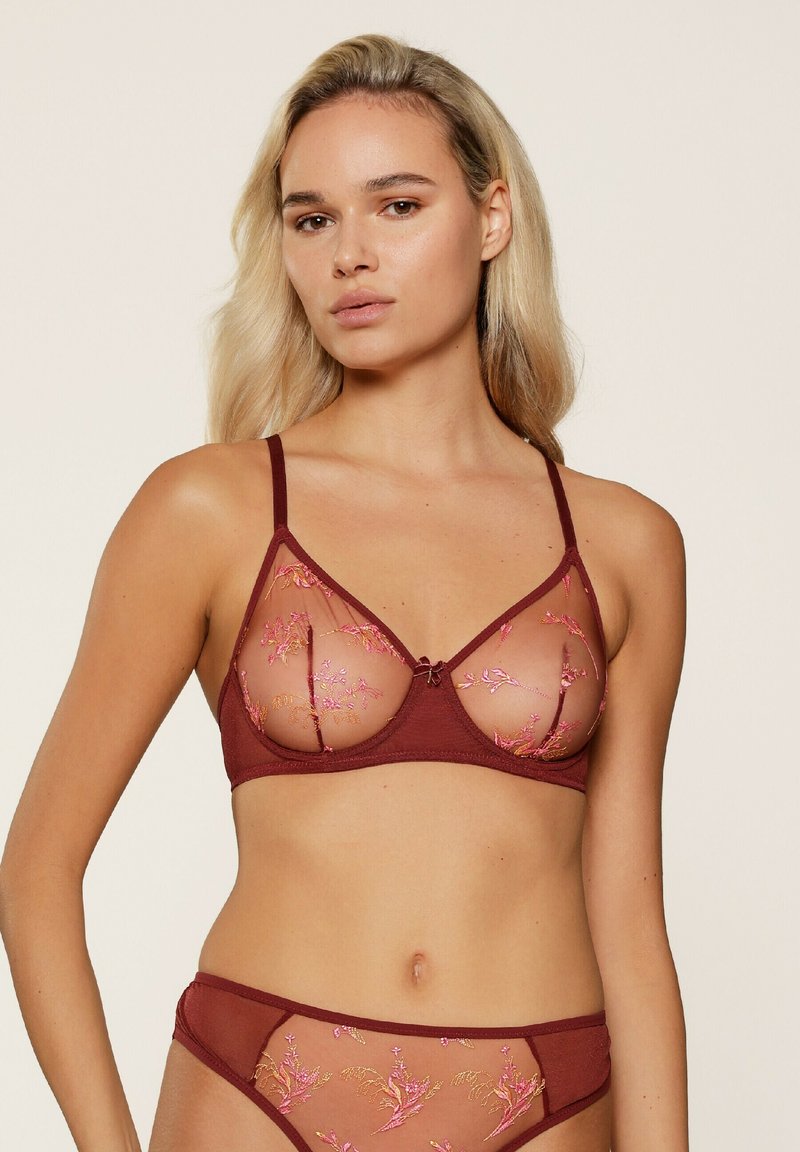 Bordeaux bh met doorzichtige mesh cups, geborduurde bloemenpatronen in het roze en verstelbare bandjes. Heeft een strikdetail in het midden.