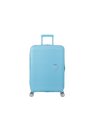 Valigia rigida azzurro chiaro con manico telescopico esteso, design a cerchi concentrici testurizzati e quattro ruote girevoli su sfondo bianco.
