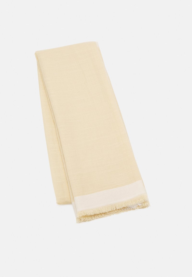 Écharpe en tissu plié de couleur crème avec une texture tissée subtile et des bords frangés à une extrémité.
