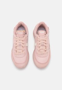 Chaussures de sport roses avec une tige en tissu lisse, un bout arrondi, des accents texturés et des lacets plats. Marquage sur la languette et le côté.