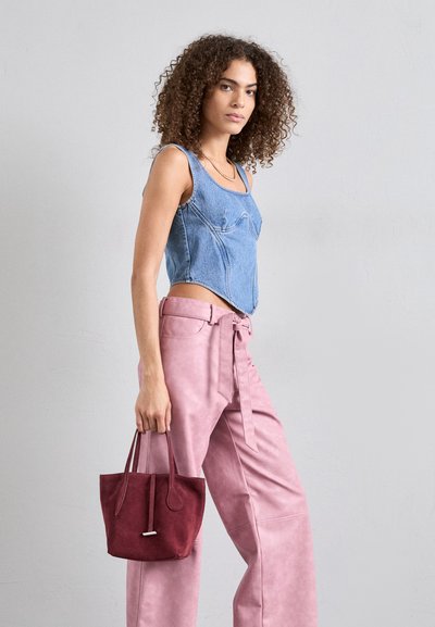 Džínová crop top s zakrivenými švami, svetlomodrej farby; skombinovaná s ružovými nohavicami z faux kože s vysokým pásom a malou bordovou semišovou taškou.