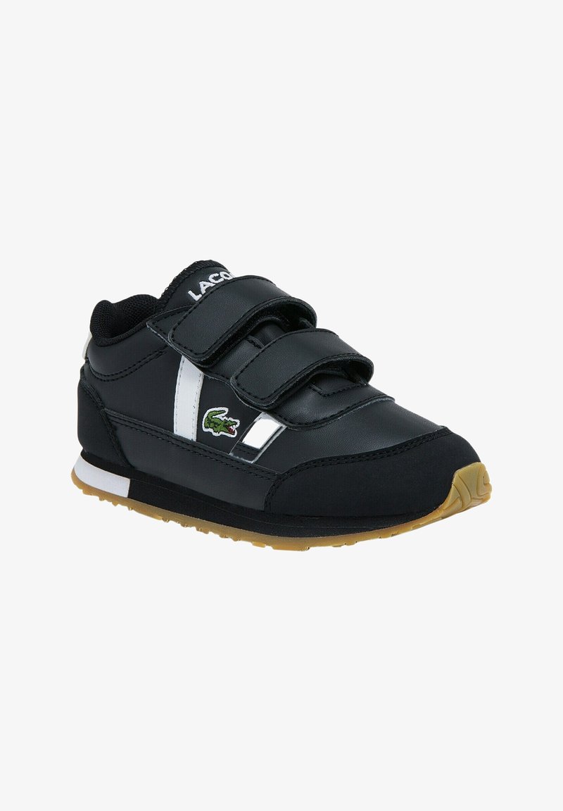 Chaussures de sport noires avec des sangles Velcro, des accents blancs et un logo de crocodile vert. Semelle en gomme et tige en synthétique texturé.