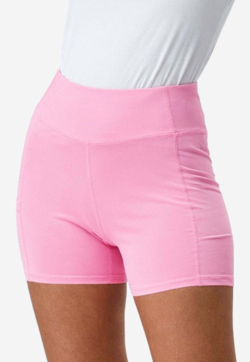 Hoch taillierte, enganliegende pinke Sportshorts, getragen mit einem weißen Oberteil, sichtbar von der Taille bis zur Mitte des Oberschenkels bei einer Person mit brauner Haut.