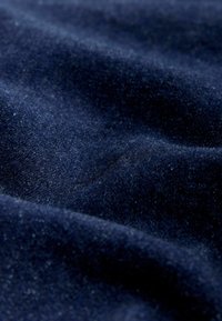 Navyblauer Samtstoff mit einer weichen, strukturierten Oberfläche. Das Material weist einen leichten Glanz auf, mit sichtbaren Fasern und sanften Falten.