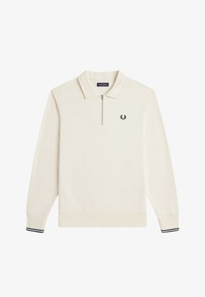 Polo à manches longues couleur crème avec une fermeture éclair au quart, des poignets côtelés avec des rayures noires et un petit logo de couronne de laurier noire sur la poitrine.
