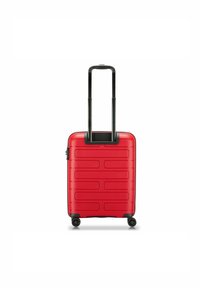 Red hard-shell suitcase with a grooved design, black retractable handle, and four wheels for maneuverability. Compact and structured shape.