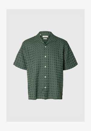 Chemise verte foncée à manches courtes avec boutons, texture à carreaux subtile et col classique sur fond uni.