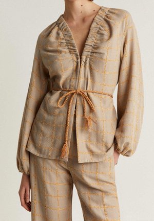 Beiges langärmliges Oberteil und Hose mit orangem Karomuster, gerafftem Ausschnitt, elastischen Bündchen und einem geflochtenen Gürtel, der in der Taille gebunden ist.