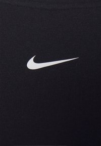 Tissu athlétique noir avec un motif de tricot texturé, arborant un logo Swoosh blanc de Nike en évidence sur le côté gauche.