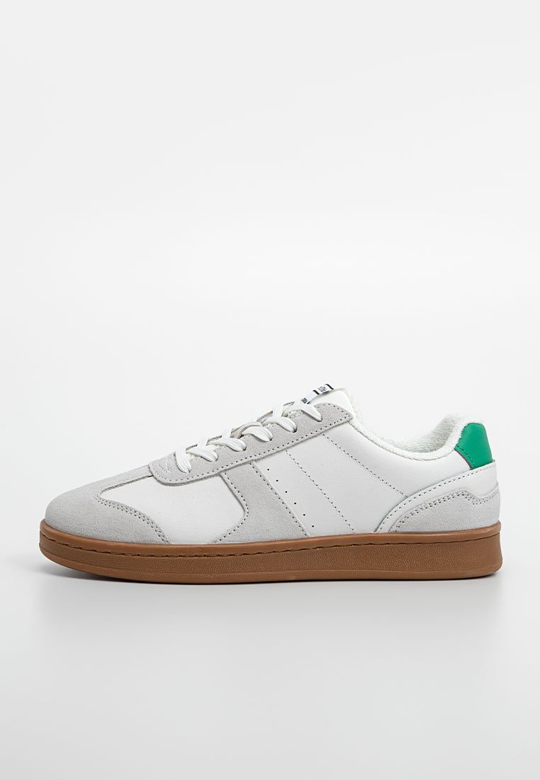 Białe sneakersy z szarymi zamszowymi akcentami, zieloną pętelką na pięcie, płaskimi sznurowadłami i brązową gumową podeszwą. Posiadają perforowane detale po bokach.