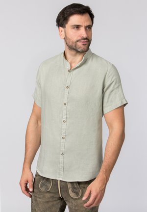 Kurzärmliges, hellgrünes Leinenhemd mit Stehkragen, mit Knopfleiste und subtiler Textur. Getragen mit braunen bestickten Hosen.