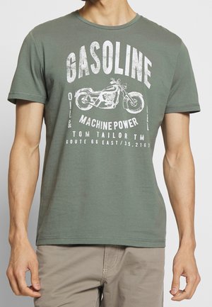 Mand iført olivengrøn T-shirt med hvidt motorcykelmotiv og tekst "Gasoline Machine Power Tom Tailor TM Route 66 East."