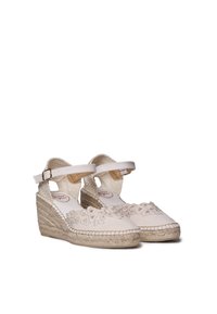 Weiße Leinwand-Espadrilles mit gesticktem Blumenmuster, Knöchelriemen und geflochtener Jute-Keilsohle. Glatte Textur, abgerundete Zehenpartie und weicher Stoff.