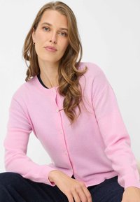 Cardigan rosa realizzato in tessuto morbido con scollo rotondo, chiusura con bottoni e maniche lunghe, caratterizzato da una texture liscia e un design minimalista.