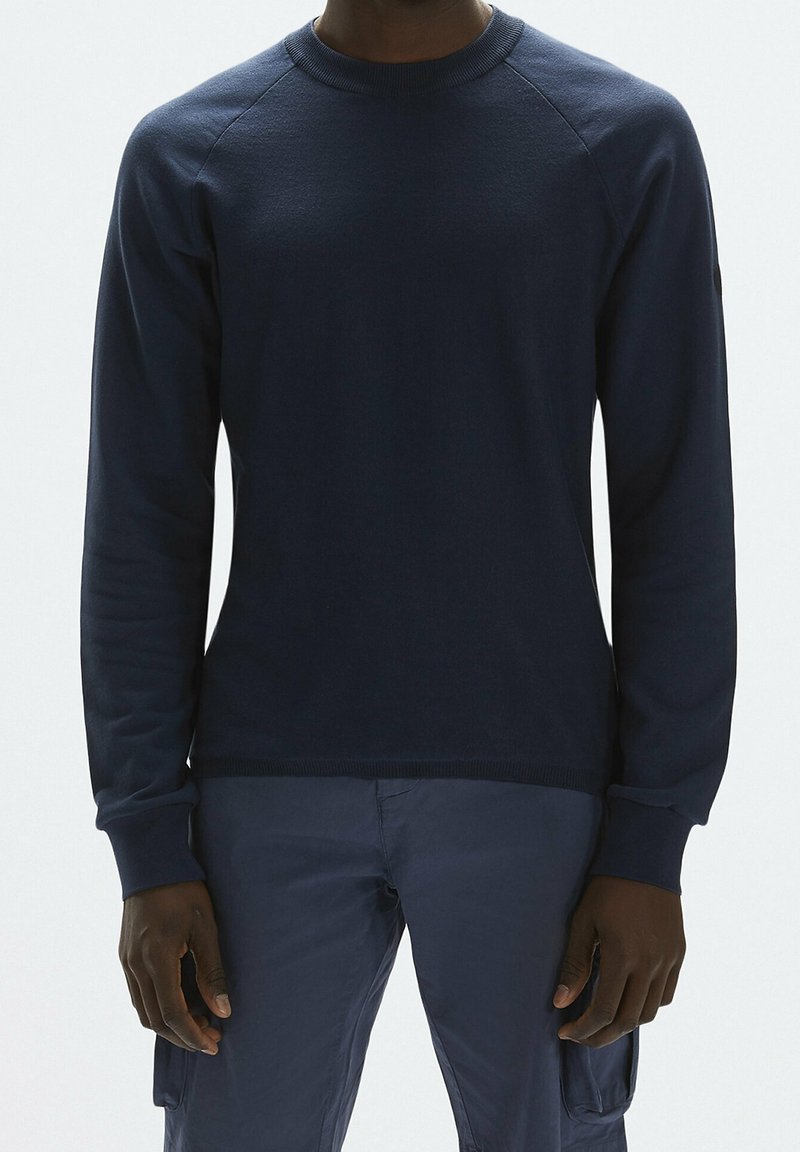 Sweat-shirt bleu marine avec un col rond côtelé et de longues manches raglan, fabriqué dans un matériau doux, présentant une finition texturée et sans logos visibles.