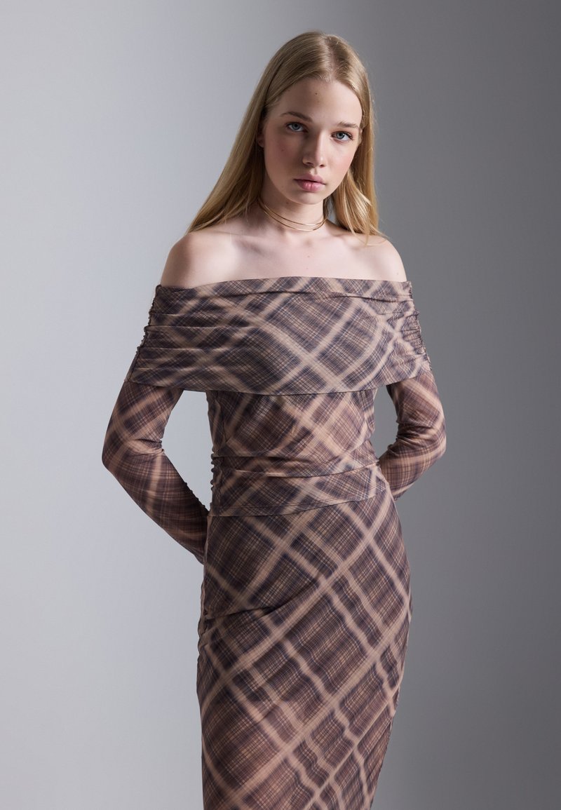 Brun off-the-shoulder kjole med rutete mønster. Har lange ermer, rynket tekstur, og en tilpasset design som strekker seg til midtleggen.