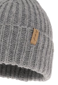 Gray knit beanie with vertical ribbing pattern, showcasing a textured finish. Features a small, light brown fabric tag on the side.