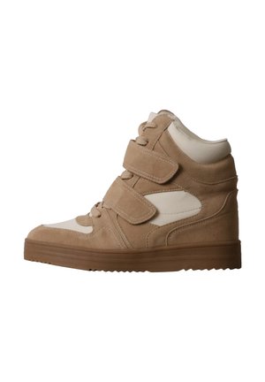 Basket montante beige avec deux bandes Velcro, lacets à l'avant et semelle épaisse marron, vue de côté sur fond blanc.