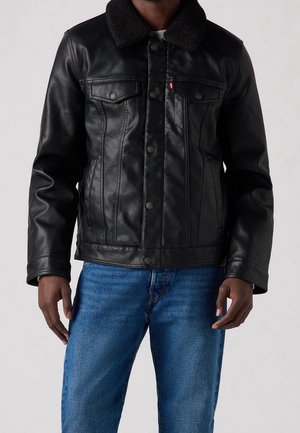 Veste en cuir noire avec un col en shearling, des boutons-pression et deux poches poitrine. Elle présente un design classique de veste en denim avec un léger éclat.