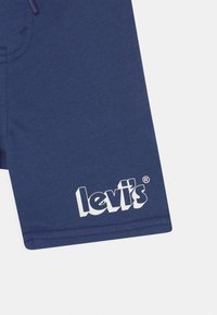 Námořnické modré bavlněné šortky s hladkým povrchem a bílým logem "levi's" potištěným blízko lemu. Mají stahovací pas pro úpravu.