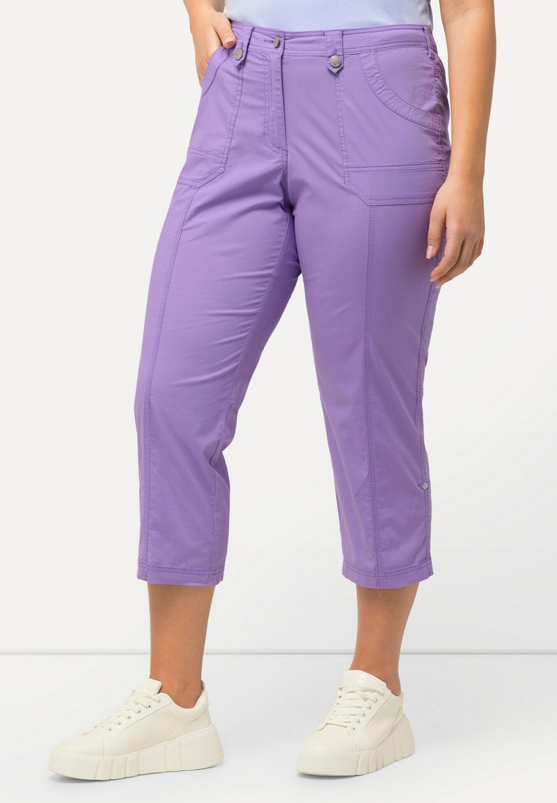 Pantalons courts violets en tissu doux, dotés de deux poches avant, de détails de couture subtils et de boutons métalliques. Assortis avec des baskets blanches.