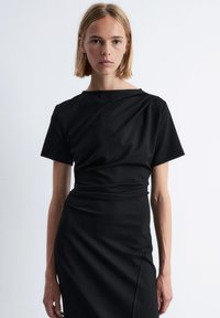 Schwarzes Kleid mit kurzen Ärmeln, aus glattem Stoff gefertigt. Verfügt über einen drapierten Ausschnitt und eine taillierte Silhouette mit minimalen Details.