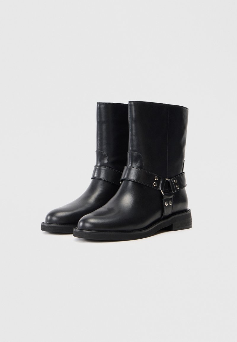 Schwarze Leder Stiefeletten mit glatter Oberfläche, ausgestattet mit einem breiten Riemen und einem metallischen Schnallen-Detail sowie einem stabilen niedrigen Absatz.