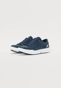 Baskets de sport bleu marine avec une tige synthétique lisse, semelle en caoutchouc blanche, design à lacets et grip texturé au fond.