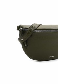 Borsa a tracolla in pelle verde oliva dalla forma curva, superficie testurizzata e chiusura con zip. Presenta una tracolla embossata e un branding sottile.
