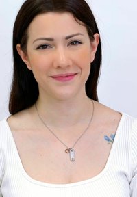 Collana d'argento con pendente testurizzato e ciondolo circolare, indossata su un top bianco a coste, su uno sfondo uniforme.