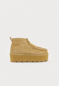 Gaiši brūni zamšaini potītes zābaki ar noapaļotu purngalu, auklām priekšā un masīvu pamatni. Iekļauts cilpiņa vieglai uzvilkšanai.