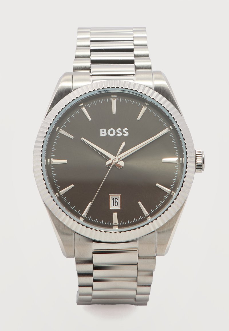 Ασημένιο ρολόι χειρός με μαύρο καντράν, ασημένιους δείκτες ώρας, ένδειξη ημερομηνίας στις 6 η ώρα και λογότυπο "BOSS" κάτω από τις 12 η ώρα σε μπρασελέ από μεταλλικούς κρίκους.