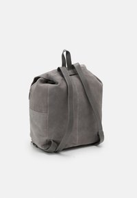 Szara skórzana plecak o zaokrąglonym kształcie, z regulowanymi paskami i górnym otwarciem. Posiada akcenty w postaci szwów oraz boczną kieszeń.