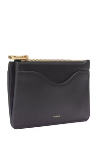 Porte-cartes en cuir noir avec poche frontale incurvée, fermeture éclair dorée et logo "VINCE." embossé en doré sur le bas devant.