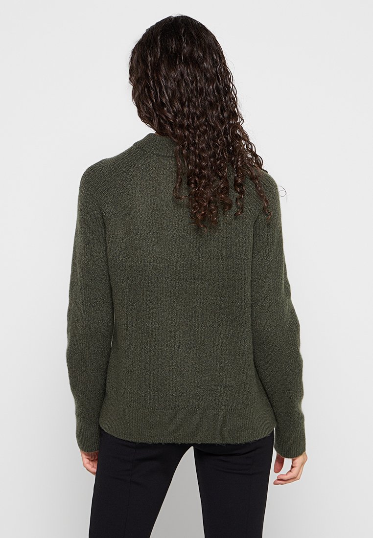 Maglione a collo alto di colore verde oliva, lavorato a maglia con una finitura testurizzata e polsini a coste, visto da dietro.