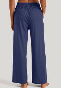 Marineblauwe wijde broek met een elastische taille, gemaakt van zachte stof, met zijzakken en een gladde textuur.