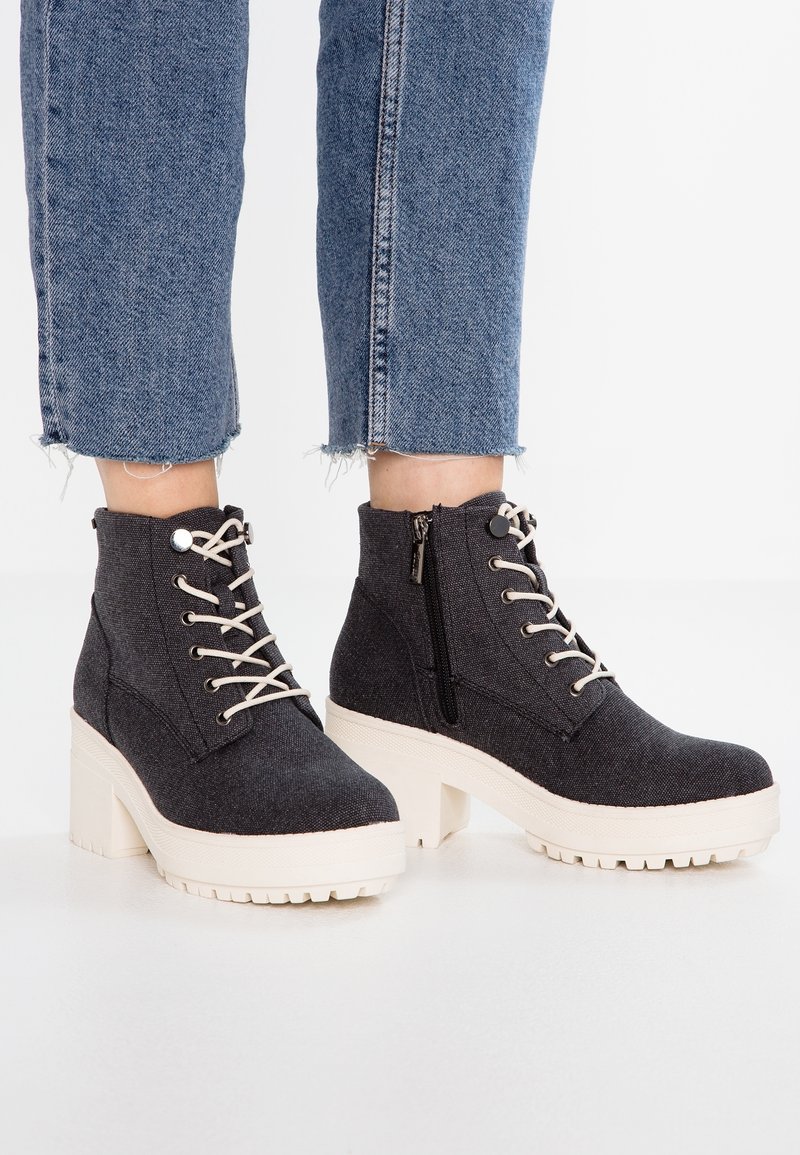 Stivaletti alla caviglia in tessuto grigio scuro con suole platform bianche, dotati di lacci frontali e una cerniera laterale per una facile vestibilità.