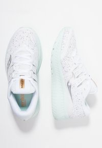Bílé sportovní boty s texturovaným svrškem, mentolově zelenou podrážkou a stříbrnými akcenty. Disponují polstrovaným interiérem a nastavitelným šněrováním.