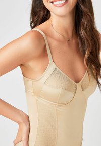 Nude shapewear met verstelbare bandjes, voorzien van een kanten paneelontwerp op het bovenste gedeelte en een gladde, naadloze afwerking.
