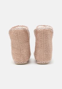 Soft pink knitted slippers with textured rope material, white patterned trim along the edges, and a cushioned interior lining.